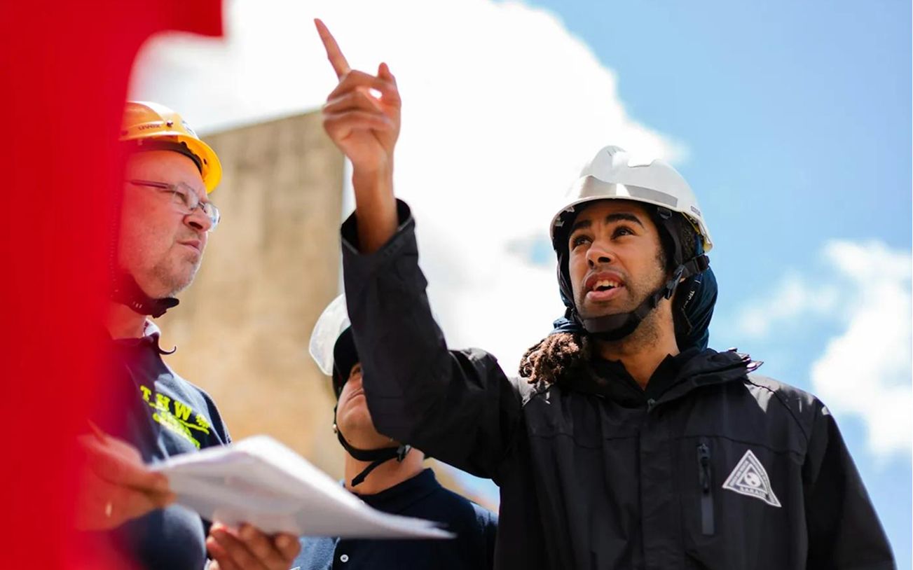 Técnicos con casco de seguridad revisando un proyecto en obra