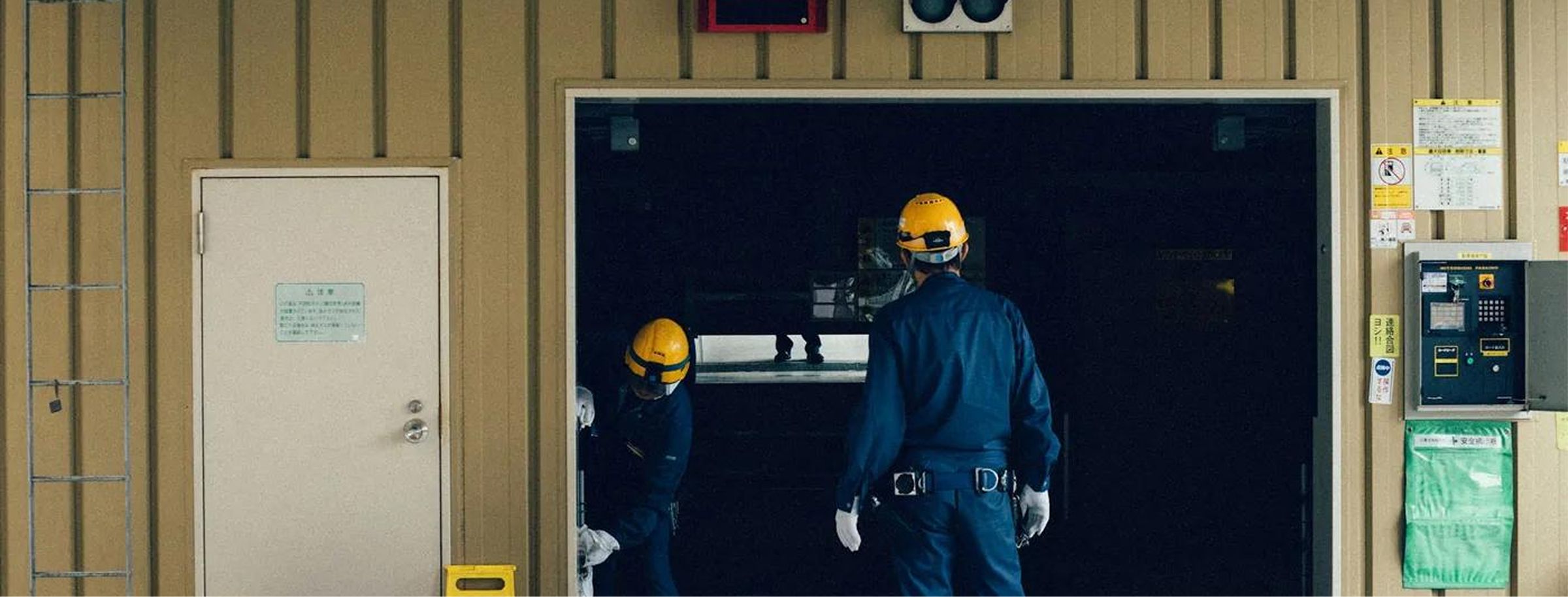 Dos técnicos con casco y uniforme entrando en una sala de instalaciones